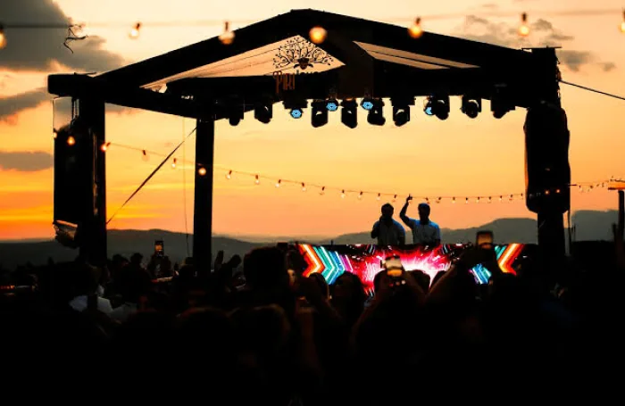Palco ao ar livre ao pôr do sol com público em silhueta