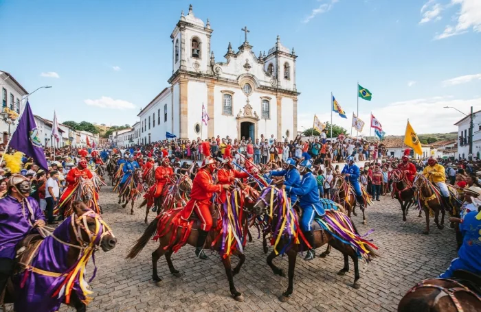 Cavalhadas diante da Igreja Matriz, com cavaleiros enfeitados e público nas ruas